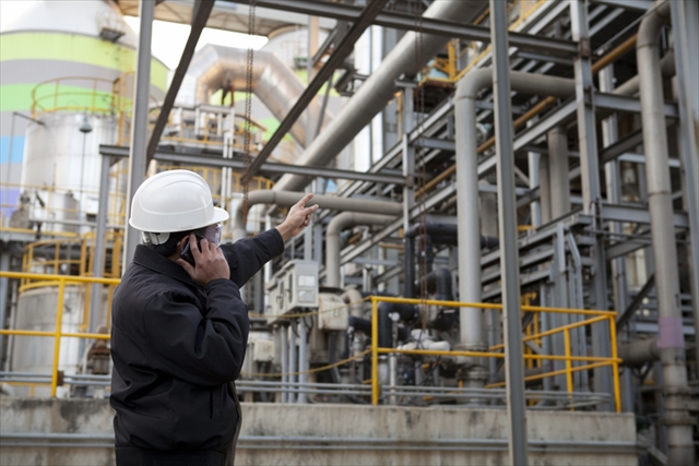 oil refinery engineer pointing against pipeline